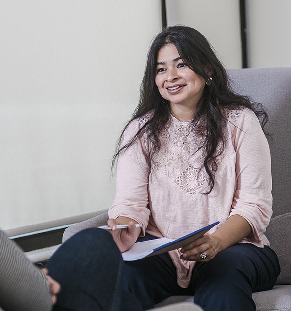 Female student holding a notepad and pen while meeting with a client in a counseling office