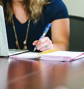 Female undergraduate accounting student taking handwritten notes during class at Cornerstone University