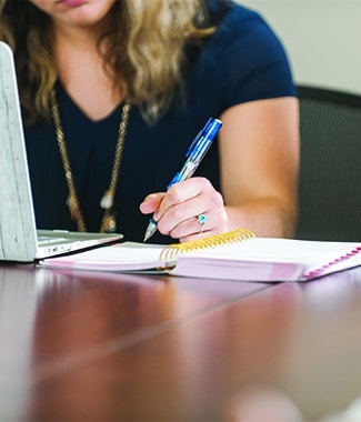 Female undergraduate accounting student taking handwritten notes during class at Cornerstone University