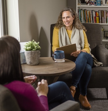 Adult female counselor holding a clipboard and pen while meeting with a client in a counseling office