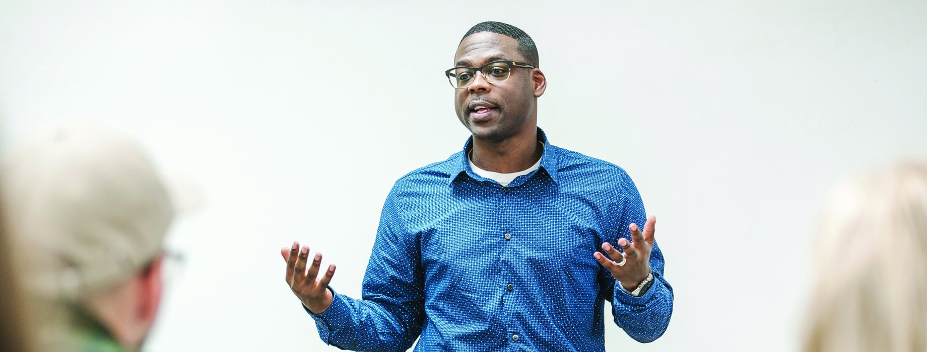 Male student speaking in front of classroom while standing behind a wooden podium