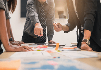 Several employees gathered around a table while working on a business plan