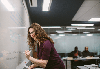 Female student writing on the whiteboard in a classroom at Cornerstone University's Professional & Graduate Studies