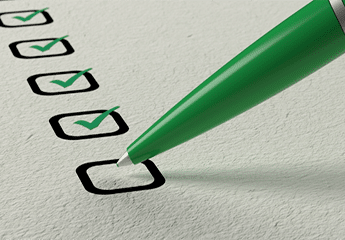 Green pen making a green checkmark on a piece of paper with boxes