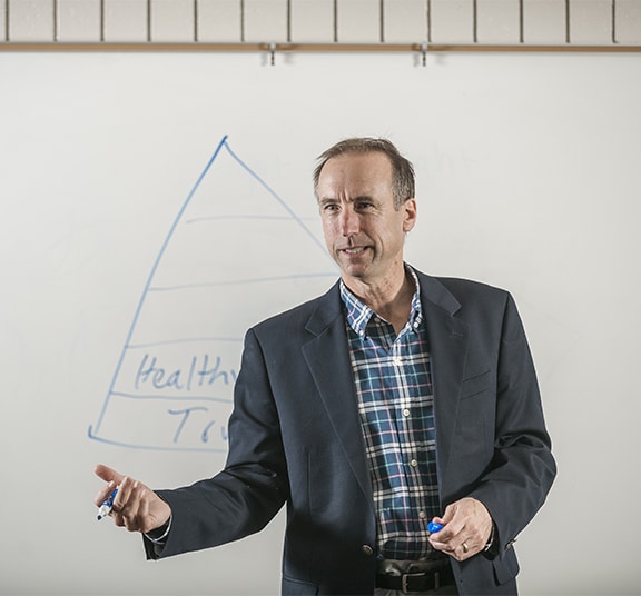Vice president of advancement leading a business meeting and using a whiteboard to present a concept to staff at Cornerstone University