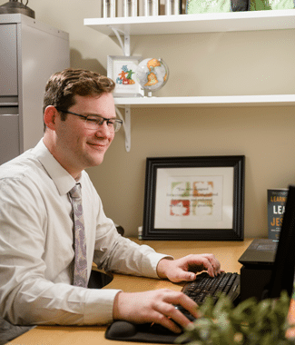 Male employee typing on his computer at his desk in his workplace