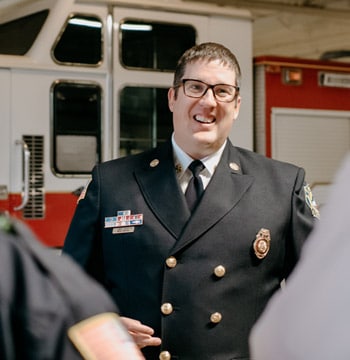 Male leader in uniform talking to three employees in fire department garage
