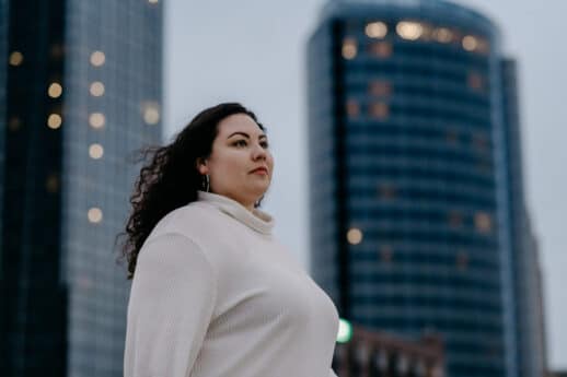 Adult female looking in the distance while standing in downtown Grand Rapids, Michigan, with buildings in the background