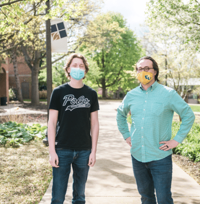 Male student and professor standing on the sidewalk located outside of the dining commons at Cornerstone University