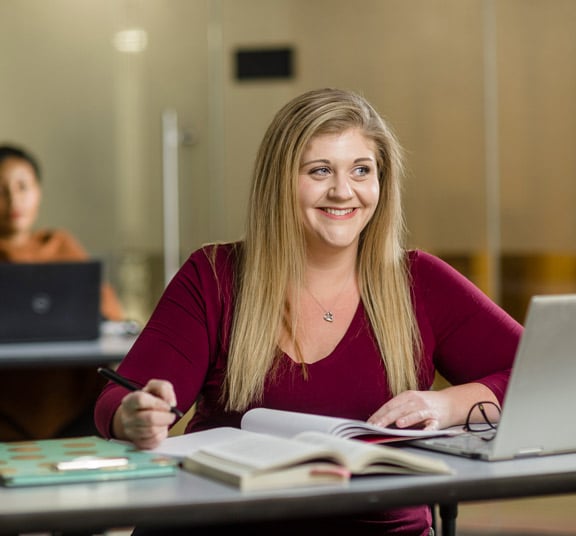 Female student taking handwritten notes in an adult business class at Cornerstone University