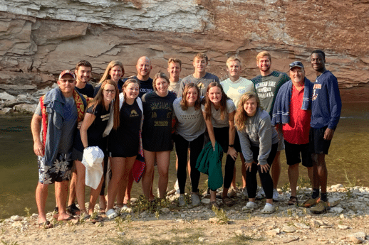 Male and female student-athletes and Cornerstone University staff standing by river
