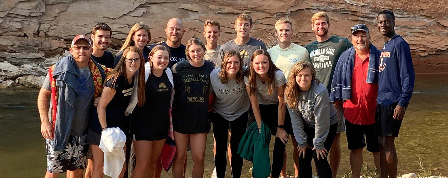 Male and female student-athletes and Cornerstone University staff standing by river