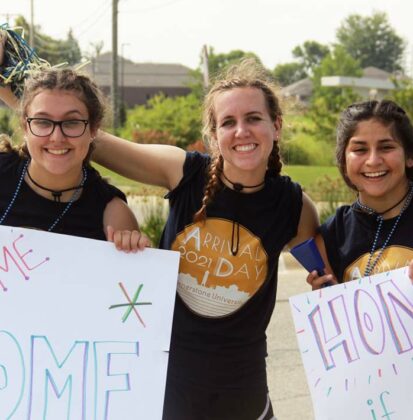 Female Cornerstone University students holding handwritten signs to welcome new students to campus for Arrival Day 2021