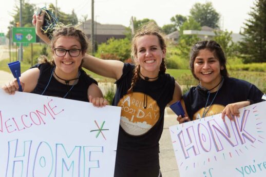 Female Cornerstone University students holding handwritten signs to welcome new students to campus for Arrival Day 2021
