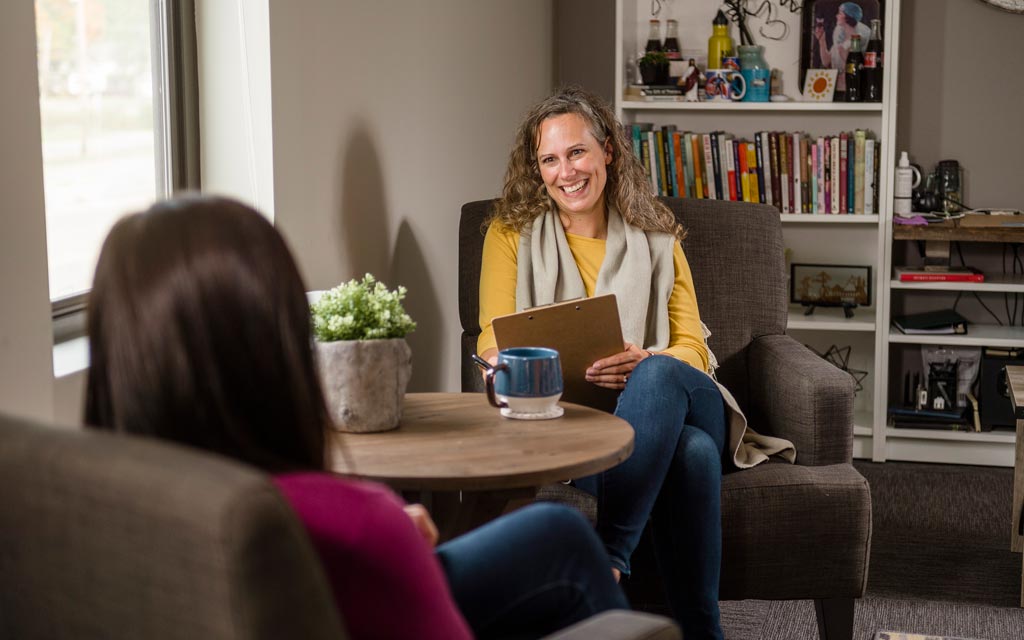 Female counselor meeting with a female client by a round table in an office setting