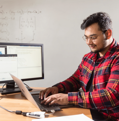 Male student typing on a laptop in a data engineering classroom