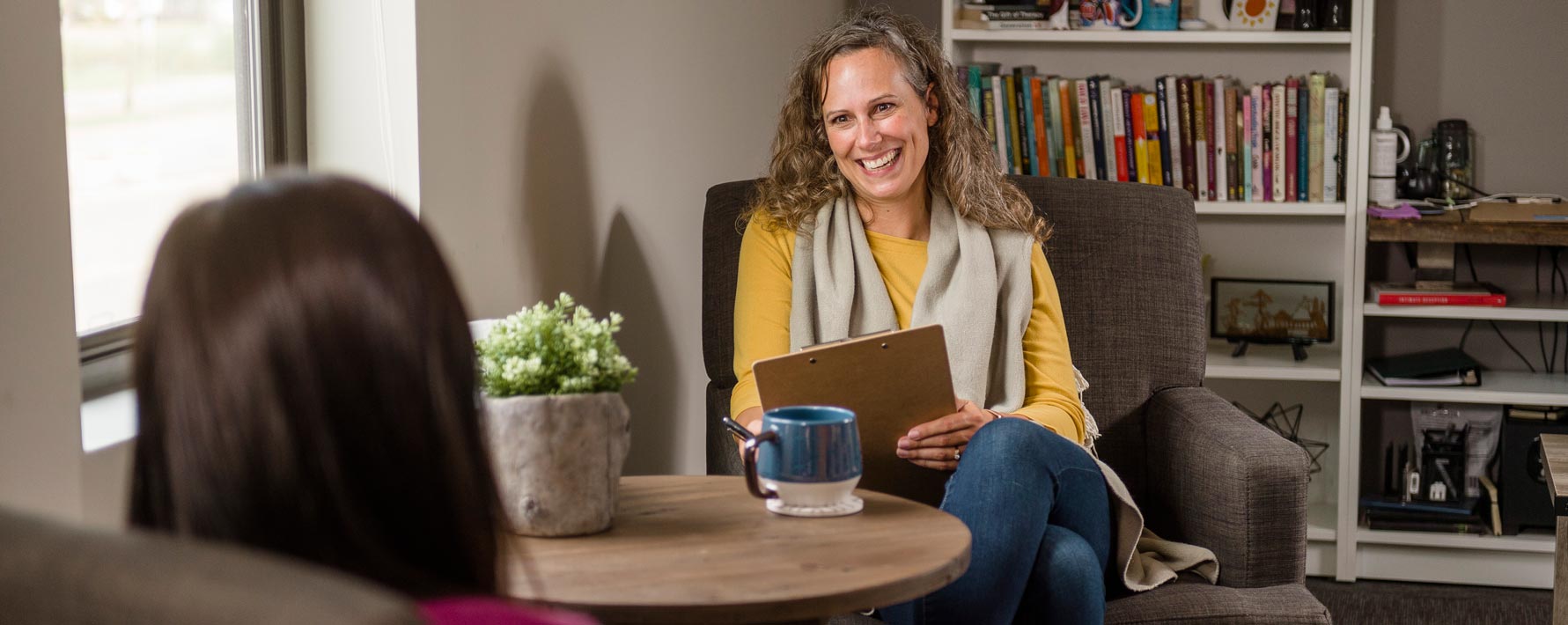 Female counselor meeting with a female client by a round table in an office setting