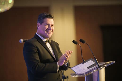 Gerson Moreno-Riaño stands behind a podium at Cornerstone University's Inaugural Gala in a tuxedo