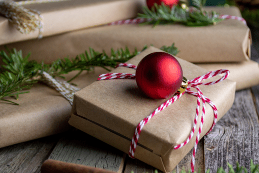 Christmas gifts wrapped in brown paper and tied with red and white striped twine with pine branches and round ornaments