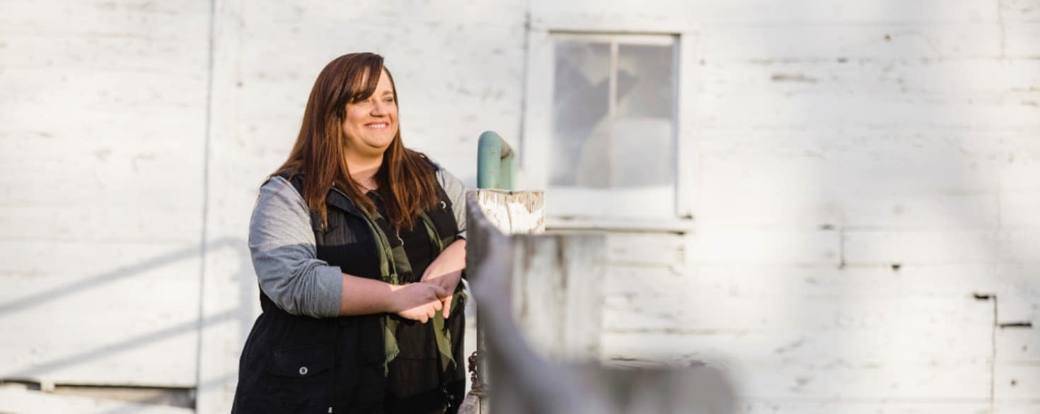 Female psychology student at Cornerstone University stands at a fence in her yard