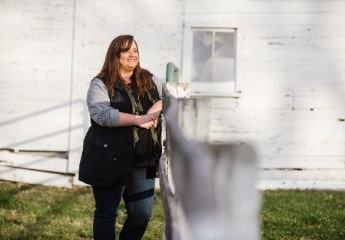 Female psychology student at Cornerstone University stands at a fence in her yard