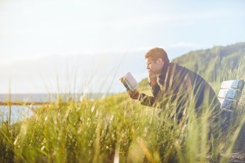 Man sitting outside reading a book