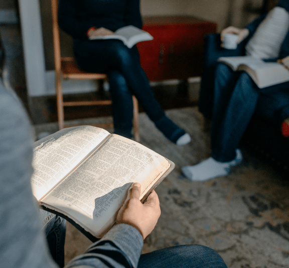 Person holding an open Bible while sitting in a living room