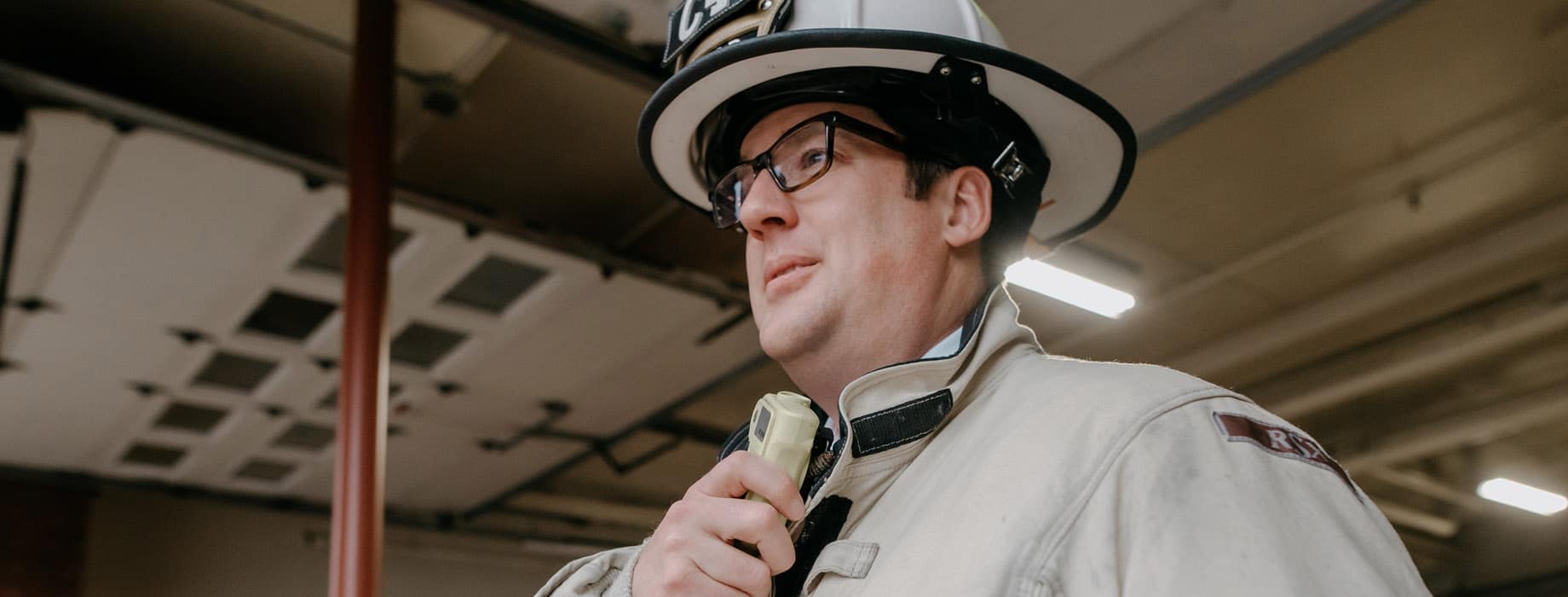 Male firefighter holding radio while standing in a fire station