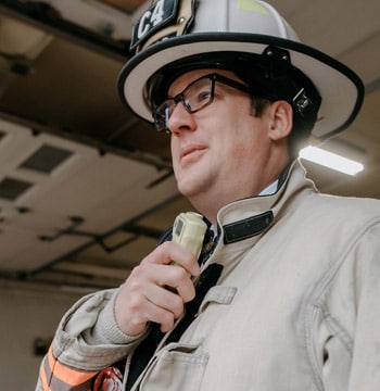 Male firefighter holding radio while standing in a fire station