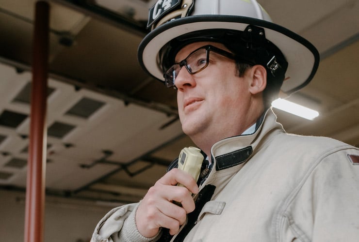 Male firefighter holding radio while standing in a fire station