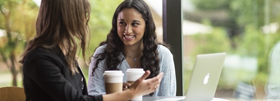 Adult female meeting with female student at a table with a laptop and coffee cups