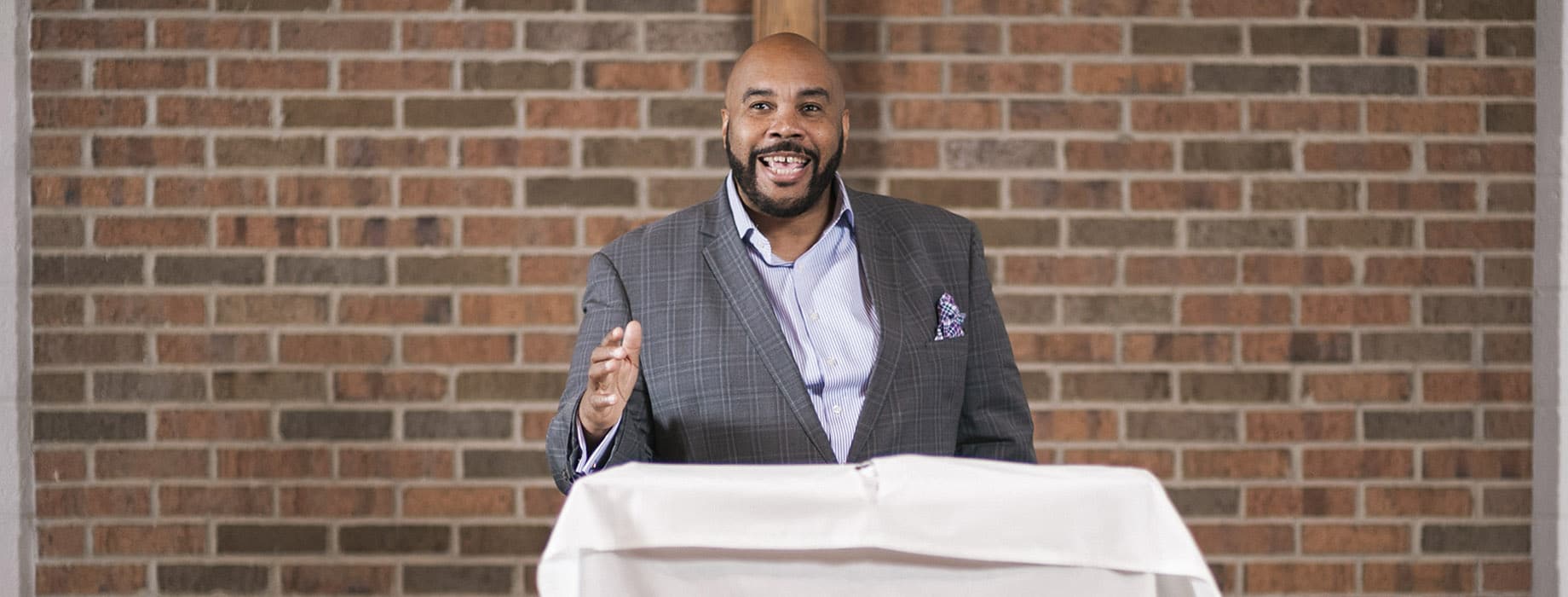 Adult male in a business suit speaking from a lectern in a sanctuary