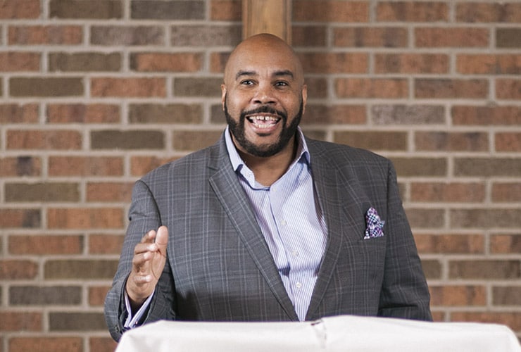Adult male in a business suit speaking from a lectern in a sanctuary