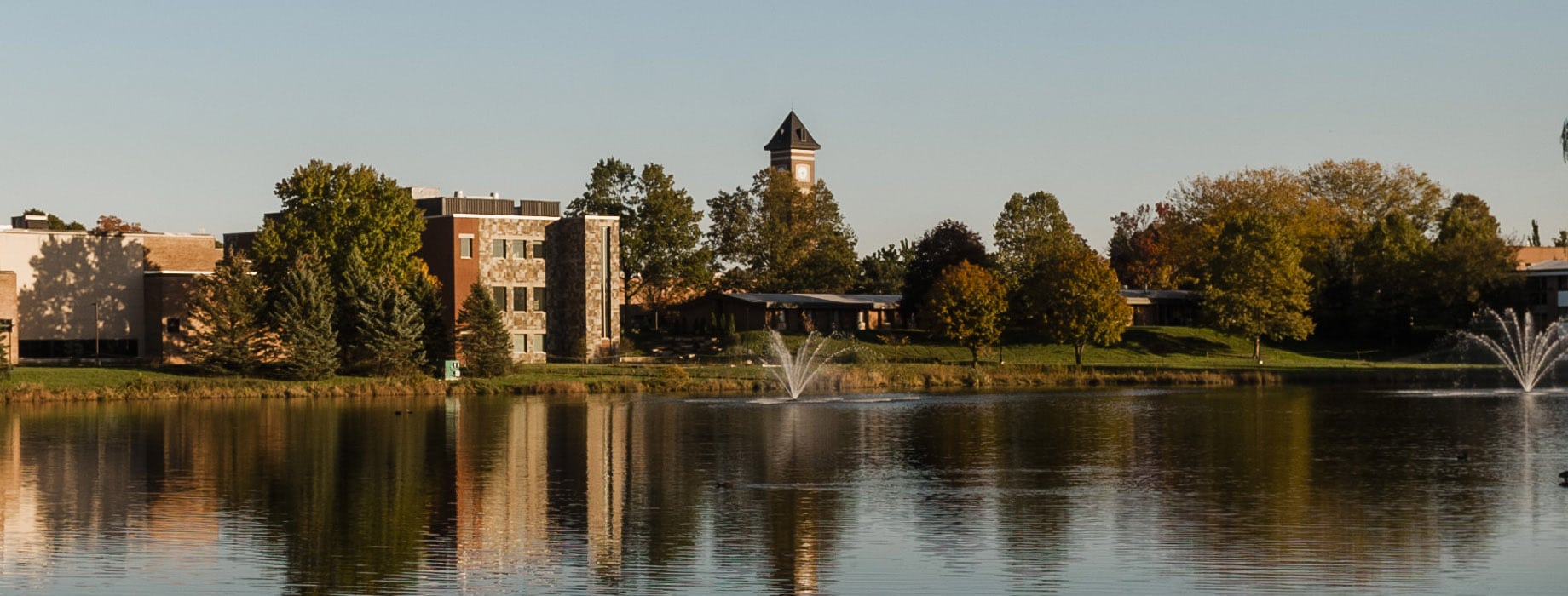 Cornerstone University campus pond and fountain with De Witt Center for Science & Technology and campus bell tower in the background