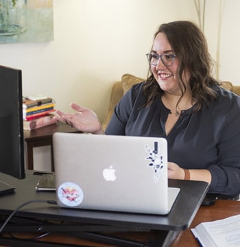 Female graduate student taking an online class on a laptop in a home living room