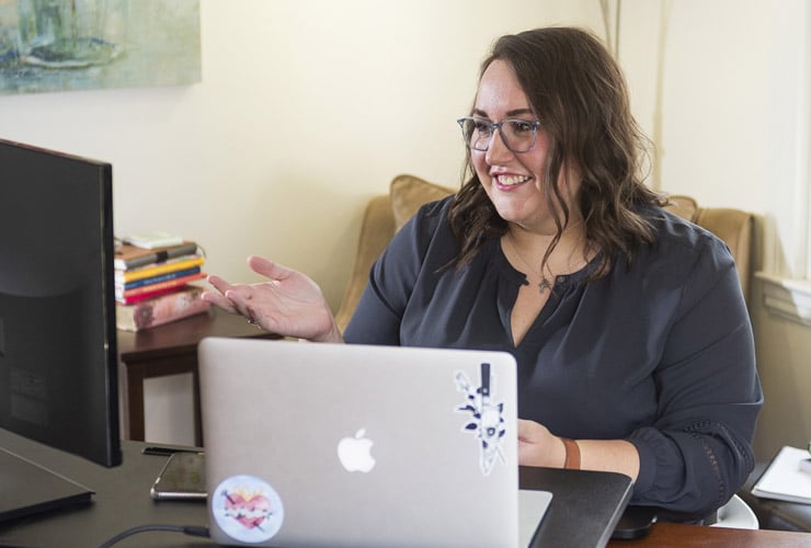Female graduate student taking an online class on a laptop in a home living room