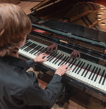 Male playing a grand piano in Matthews Performing Arts Center at Cornerstone University