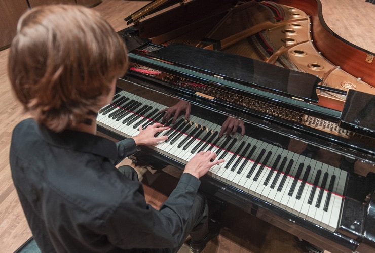 Male playing a grand piano in Matthews Performing Arts Center at Cornerstone University