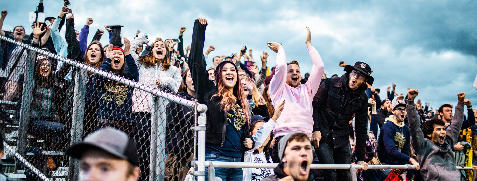 College students and fans standing and cheering in bleachers