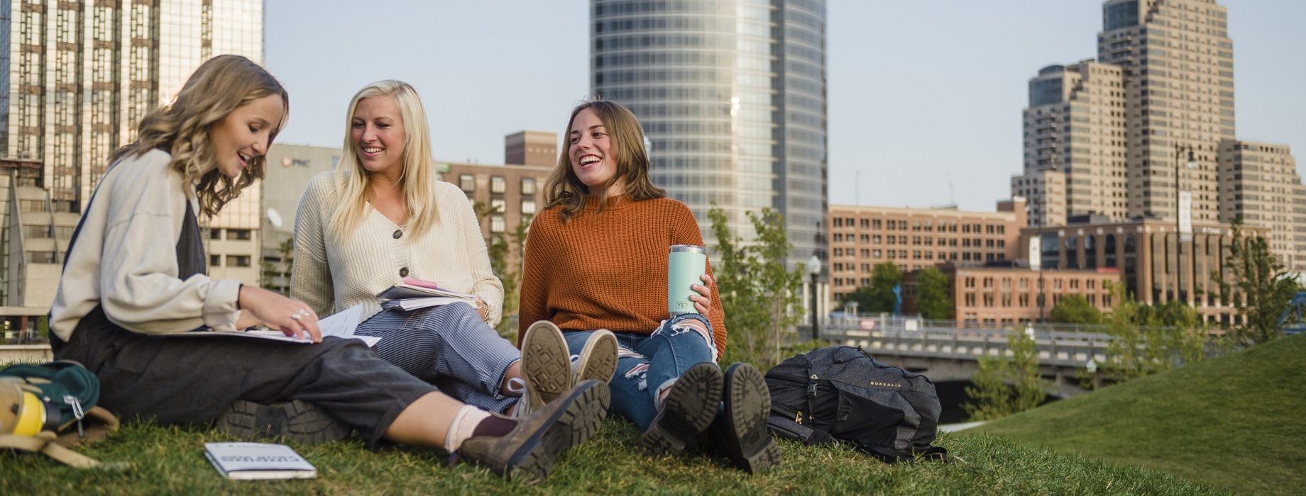 Three female college students studying outside in downtown Grand Rapids in the fall