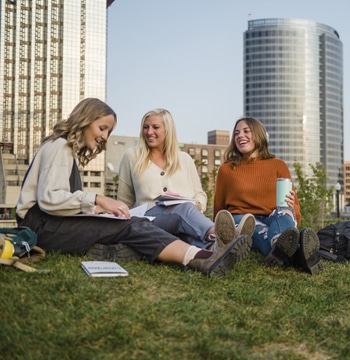 Three female college students studying outside in downtown Grand Rapids in the fall