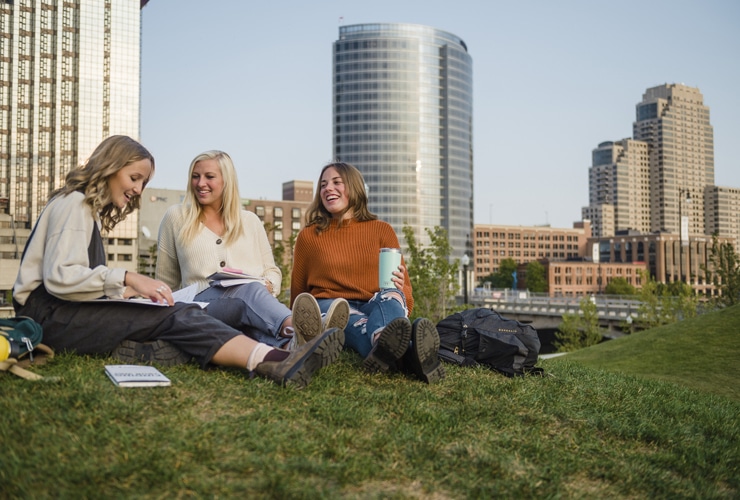 Three female college students studying outside in downtown Grand Rapids in the fall