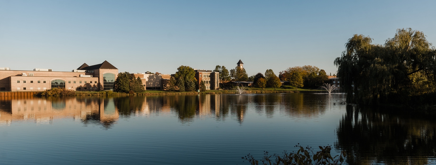 Cornerstone University athletic facility, science building and bell tower located near campus pond