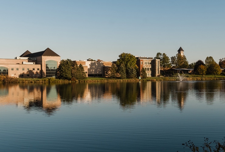 Cornerstone University athletic facility, science building and bell tower located near campus pond