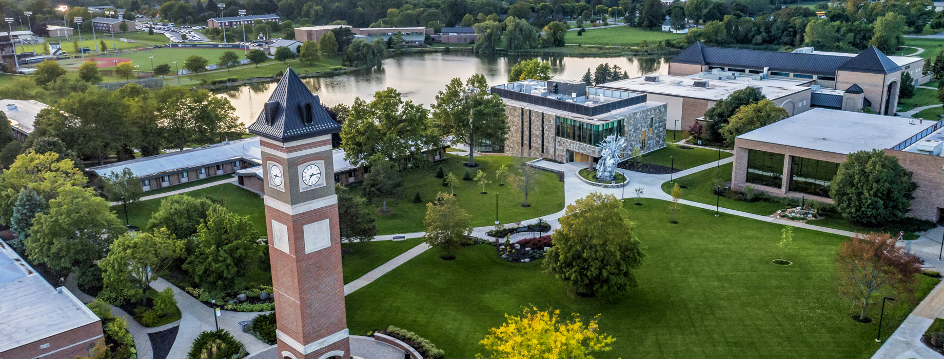 Aerial view of the Cornerstone University campus that shows academic buildings, bell tower and pond