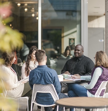 Male and female graduate students studying at table outside of coffee shop