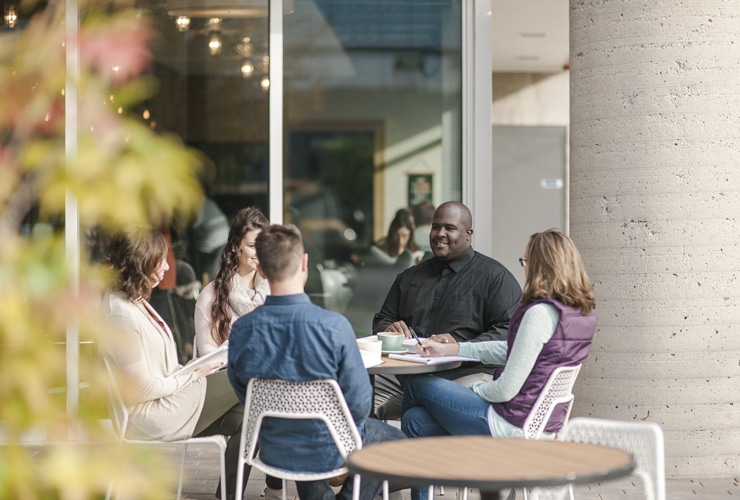 Male and female graduate students studying at table outside of coffee shop