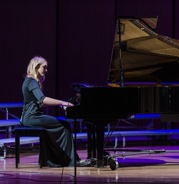 Female college student playing a grand piano in Matthews Performing Arts Center at Cornerstone University