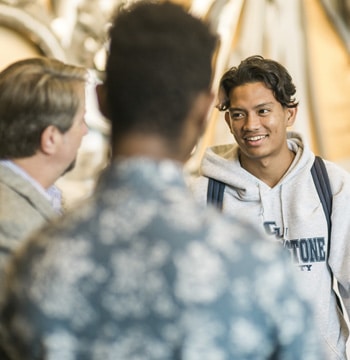Male Cornerstone University students talking with a staff member in the lobby of Christ Chapel