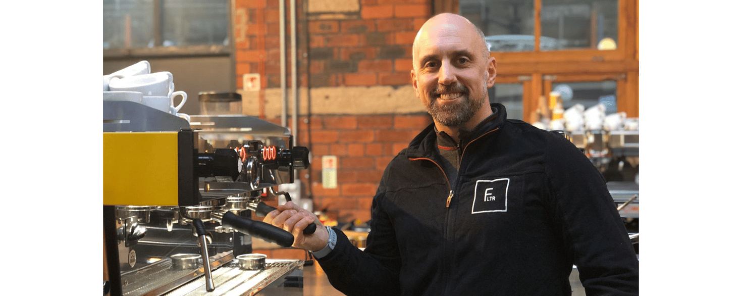 Jeff Lothamer standing in front of an expresso machine in a coffee shop